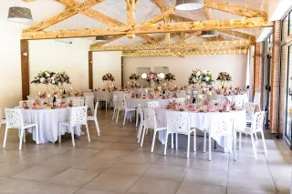 Salle de réception avec charpente apparente et briquettes rouges, dressée pour un dîner